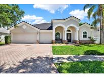 Charming home with a three-car garage, arched entryway, and a well-manicured front yard at 20835 Lake Talia Blvd, Land O Lakes, FL 34638