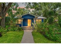 Charming blue home with lush landscaping, walkway and bright yellow door at 217 W Powhatan Ave, Tampa, FL 33604
