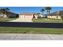 Single-story home with a 2 car garage, well manicured lawn, mature trees in the distance at 5494 Sabal Trace Dr, North Port, FL 34287