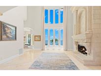 Bright living room featuring a fireplace, soaring ceilings, a large bay window with scenic water views at 611 1St S Ave, Tierra Verde, FL 33715