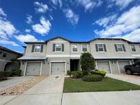 Well-maintained townhome with attached garages, beautiful landscaping, and a manicured lawn at 9768 Pembrooke Pines Dr, Sun City Center, FL 33573