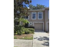 Charming townhome featuring a one-car garage and neatly maintained front yard landscaping at 9958 Ashburn Lake Dr, Tampa, FL 33610