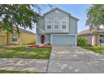 Charming light blue two-story home with a well-manicured lawn and an attached two-car garage at 11438 Ivy Flower Loop, Riverview, FL 33578
