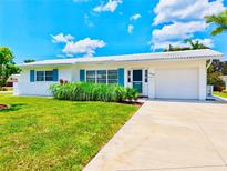 Charming single-story home boasts a well-maintained lawn, bright blue shutters, and a convenient attached garage at 14230 86Th Ter, Seminole, FL 33776