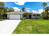 Charming single-story home features a well-manicured lawn, paved driveway, and an attached two-car garage at 14422 Chamberlain Blvd, Port Charlotte, FL 33953