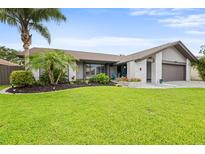 Charming single-story home with well-manicured lawn, tropical landscaping, and painted brick exterior at 1632 Ridge Top Way, Clearwater, FL 33765