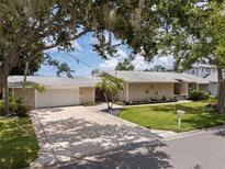 Charming single-story home with a well-manicured lawn, mature trees, and a paved driveway leading to a two-car garage at 17 Freshwater Dr, Palm Harbor, FL 34684