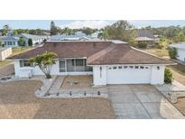 Charming home featuring a well-maintained front yard, a screened porch, and an attached two-car garage at 1732 Flamingo Ln, Sun City Center, FL 33573