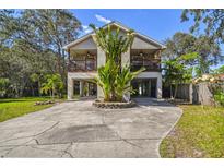 Inviting two-story home featuring dual balconies and a unique stilt foundation with landscaped yard at 5908 Mohr Rd, Tampa, FL 33615