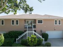 Charming two-story home with landscaped yard, featuring a staircase leading to the front door and an attached garage at 6663 Bayou Grande Ne Blvd, St Petersburg, FL 33702