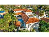 A stunning aerial view of this luxurious home featuring a red tile roof, pool, and lush landscaping at 831 Mandalay Ave, Clearwater, FL 33767