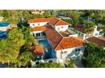 Stunning aerial view of a Mediterranean-style home with a terracotta roof, pool, and lush tropical landscaping at 831 Mandalay Ave, Clearwater, FL 33767