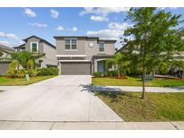 Charming two-story home with a well-maintained lawn, gray exterior, and a two-car garage at 9440 Lemon Drop Loop, Sun City Center, FL 33573