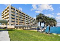 Low angle exterior of building with waterfront access and lush green lawn at 100 Bluff View Dr # 308A, Belleair Bluffs, FL 33770