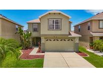 Two-story home featuring a two-car garage, manicured lawn, and beautiful landscaping at 12121 Tree Haven Ave, Gibsonton, FL 33534