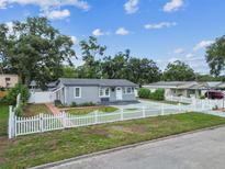 Charming gray home featuring a well-manicured lawn and classic white picket fence at 1510 W Powhatan Ave, Tampa, FL 33603