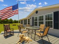 Inviting back deck with outdoor seating, ideal for enjoying the fresh air while overlooking the open backyard and featuring a loyal dog at 2221 W Lake Dr, Wimauma, FL 33598