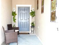 Inviting front porch with blue door, blue rug, wicker chairs, and decorative hanging plants at 30798 Veridian Way, Wesley Chapel, FL 33543