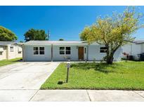 Charming single-story home with a well-maintained lawn and a welcoming facade under a clear blue sky at 3509 Brookston Dr, Holiday, FL 34691