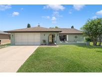 Charming single-story home featuring a lush front lawn and attached two-car garage at 7022 Kingsway Dr, Port Richey, FL 34668
