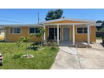 Charming single-story home with a covered porch and well-maintained lawn featuring young palm trees at 7613 Reindeer Rd, Tampa, FL 33619