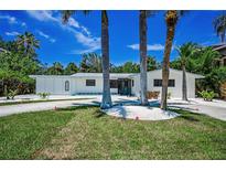 Beautiful home exterior with lush tropical landscaping and a circular driveway at 112 Peterson Ln, Palm Harbor, FL 34683