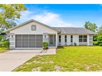 Charming single-story home with a well-maintained lawn, screened garage door, and classic design details at 12546 Brookside St, Spring Hill, FL 34609