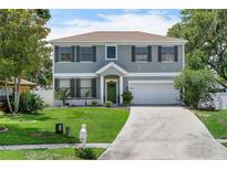 Charming two-story home featuring a well-maintained lawn, a green front door, and an attached two-car garage at 1291 Blackrush Dr, Tarpon Springs, FL 34689