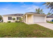 Charming one-story home featuring a two-car garage, manicured lawn, and vibrant landscaping at 13384 Brighton St, Spring Hill, FL 34609