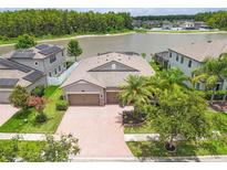 Beautiful home boasts lush landscaping and a brick driveway leading to a three-car garage and lake view at 1830 Cameron Ct, Trinity, FL 34655