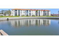Waterfront condo building with orange tile roof reflected in the water at 19029 Us Highway 19 N # 8-31, Clearwater, FL 33764