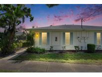 Charming white home with blue shutters, lush landscaping, and a welcoming dusk sky at 1903 Canterbury Ln # B24, Sun City Center, FL 33573