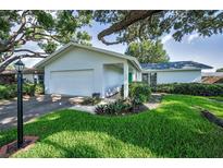 Charming single story home featuring a well-manicured lawn, attached garage, and mature landscaping at 2559 Redwood Cir, Clearwater, FL 33763