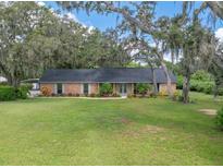 Sprawling single-story brick home with expansive front lawn and mature shade trees at 302 Old Mulrennan Rd, Valrico, FL 33594