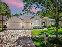 Charming home featuring a three-car garage, manicured lawn, and beautiful brick paver driveway at 3506 Cordgrass Dr, Valrico, FL 33596