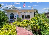 Charming home with a brick walkway and verdant landscaping beneath a clear, blue sky with white, puffy clouds at 4435 1St S Ave, St Petersburg, FL 33711