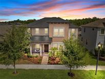 Stunning two-story home featuring a charming front porch and beautifully landscaped front yard at sunset at 4465 Tubular Run, Land O Lakes, FL 34638