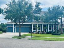 Inviting two-story home features a well-manicured lawn, a three-car garage, and striking blue exterior paint at 8332 Swiss Chard Cir, Land O Lakes, FL 34637