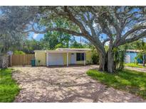 Charming yellow single-story home with a brick driveway and large shade tree in the front yard at 914 Sandpiper Way S, St Petersburg, FL 33707