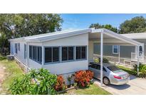 Well-maintained home featuring a carport, screened-in porch, and colorful landscaping at 9790 66Th N St # 353, Pinellas Park, FL 33782