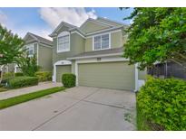 Two-story townhome with a well-maintained lawn, a two-car garage, and lush landscaping in a lovely neighborhood at 10132 Post Harvest Dr, Riverview, FL 33578