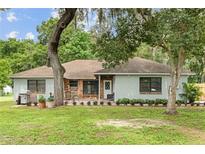 Charming single-story home featuring a brick facade, covered porch, mature landscaping, and a well-manicured lawn at 11317 Fort King Rd, Dade City, FL 33525