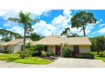 Charming single-story home with a well-manicured lawn and lush landscaping, including a tall palm tree at 13 Windrush Bay Dr, Tarpon Springs, FL 34689