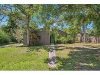 Single-story home with a long walkway to the green front door surrounded by mature trees and green lawn at 2896 Grand Cayman St, Sarasota, FL 34231