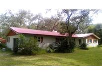Charming single-story home with red roof and painted white brick nestled in a lush, green landscape at 5540 Cyril Dr, Dade City, FL 33523