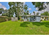 View of a home's backyard with a well-maintained lawn, trees, and a small patio area with outdoor seating at 5840 39Th N St, St Petersburg, FL 33714