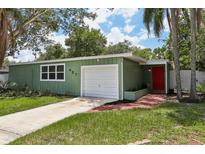 Charming single-story home with an attached garage, green exterior, and a red front door at 607 E River Dr, Temple Terrace, FL 33617