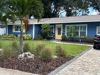 Charming single-story home boasts a vibrant blue exterior with beautiful landscaping and a brick driveway at 906 Ponce De Leon Blvd, Belleair, FL 33756
