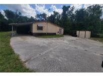 Cozy home featuring a convenient carport and expansive driveway, nestled near lush greenery and a storage shed at 9910 Jerome Dr, New Port Richey, FL 34654