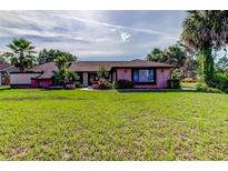 Charming brick home with a well-maintained lawn and mature palm trees under a blue sky at 10365 Lynnhaven Rd, Spring Hill, FL 34608